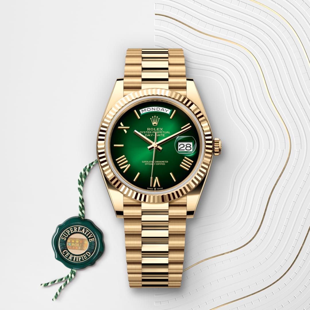 A gold Rolex watch with a green face, date display, and Superlative Certified tag on a white patterned background.