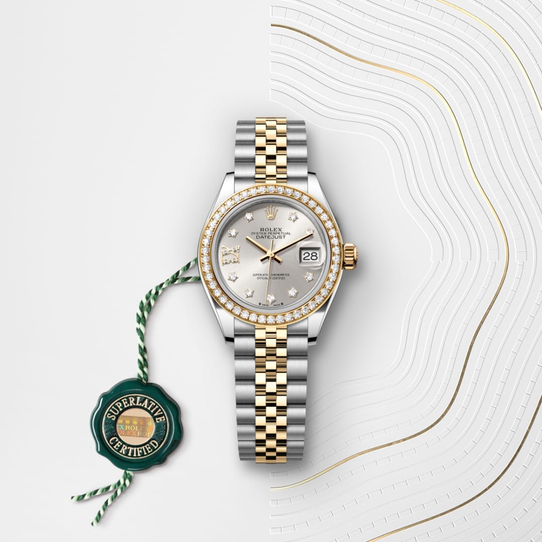 A Rolex two-tone watch with diamond hour markers, date display, and a “Superlative Certified” green seal tag.