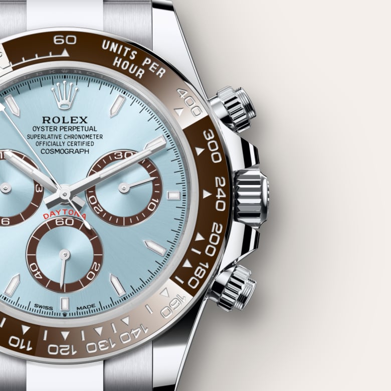 Close-up of a Rolex Daytona watch with a light blue face and brown ceramic bezel, showing detailed chronograph dials.