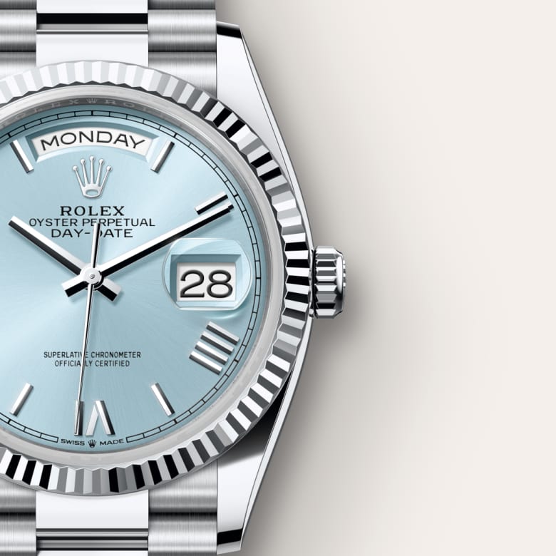 Close-up of a silver Rolex Day-Date watch with a light blue dial, showing Monday and the date 28.
