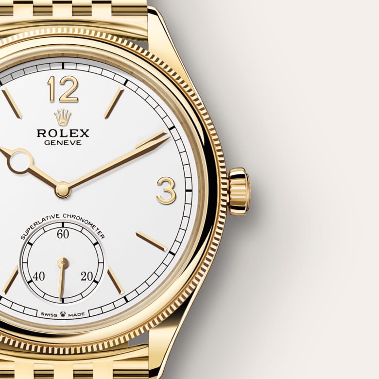 A close-up of a gold Rolex watch with a white dial and gold hour markers, showing part of the face and bezel.