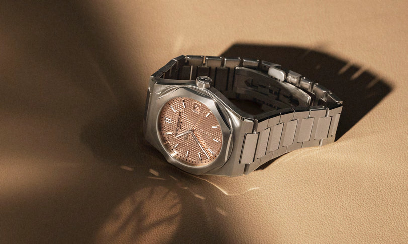Silver watch with a brown face on a beige surface