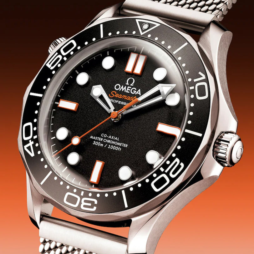 Close-up of an OMEGA Seamaster Diver 300 watch featuring a black dial, white markers, and a stainless steel mesh band.
