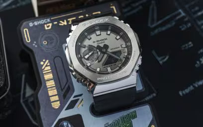 G-Shock GM2100-1ASW digital-analog watch with silver and black case on packaging background.