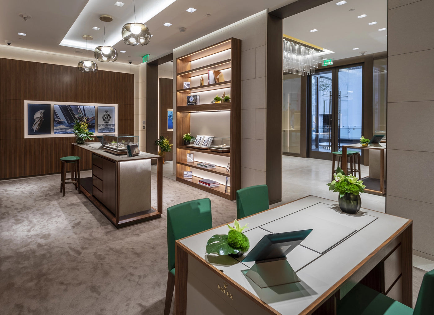 Modern, upscale retail store interior with green chairs, display cases, shelves, and decorative plants.