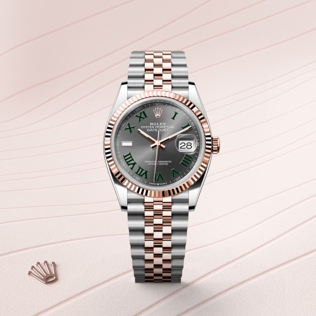 A Rolex watch with a silver and rose gold band, green Roman numerals, and a date display on a patterned background.