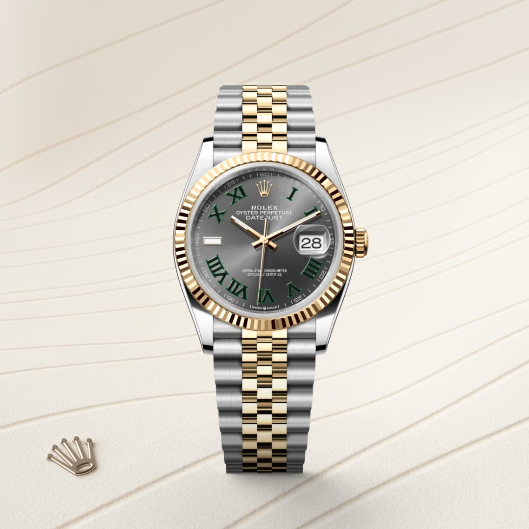 A two-tone Rolex watch with a green dial and gold fluted bezel on a light patterned background.