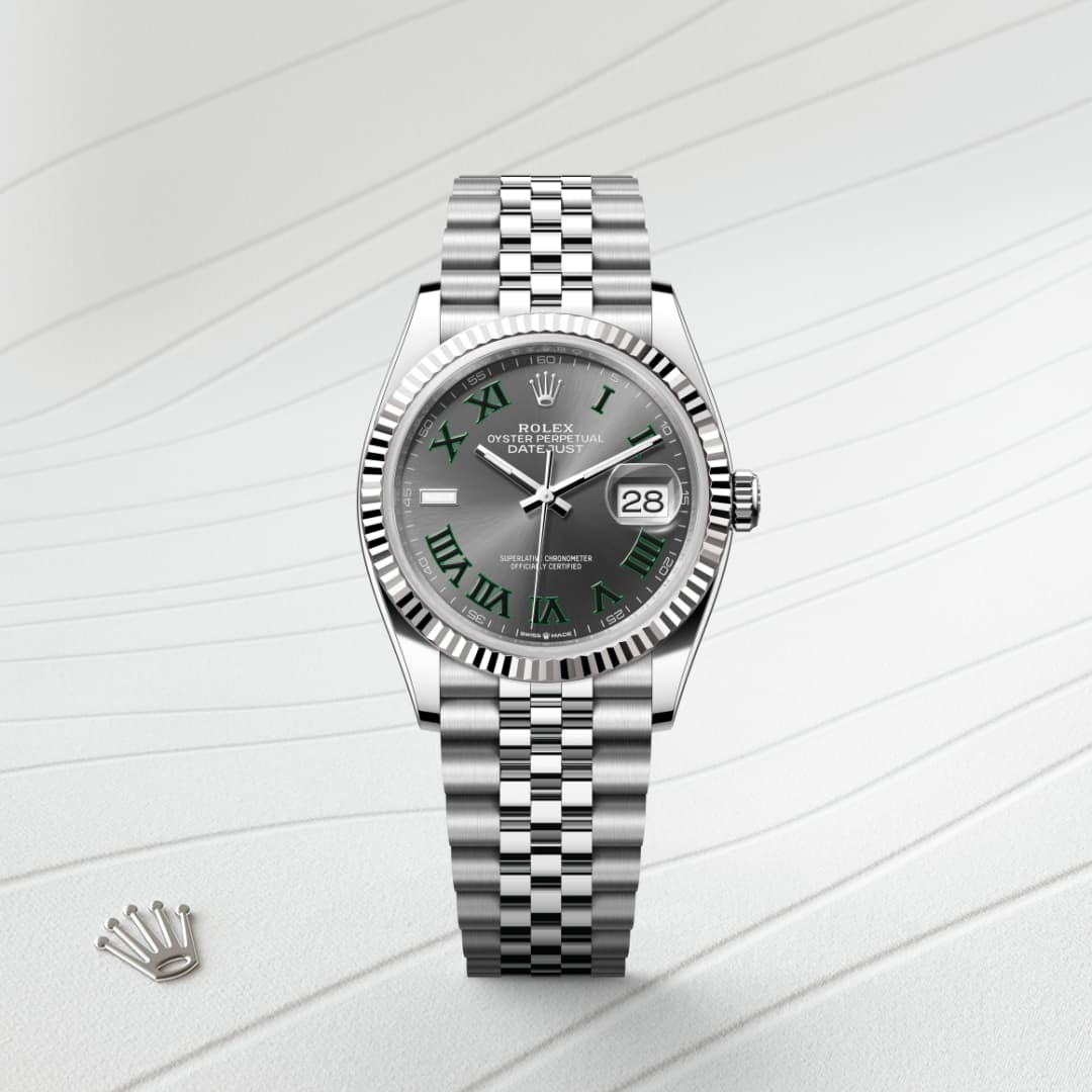 A silver Rolex watch with a green dial and Roman numerals on a textured white background.