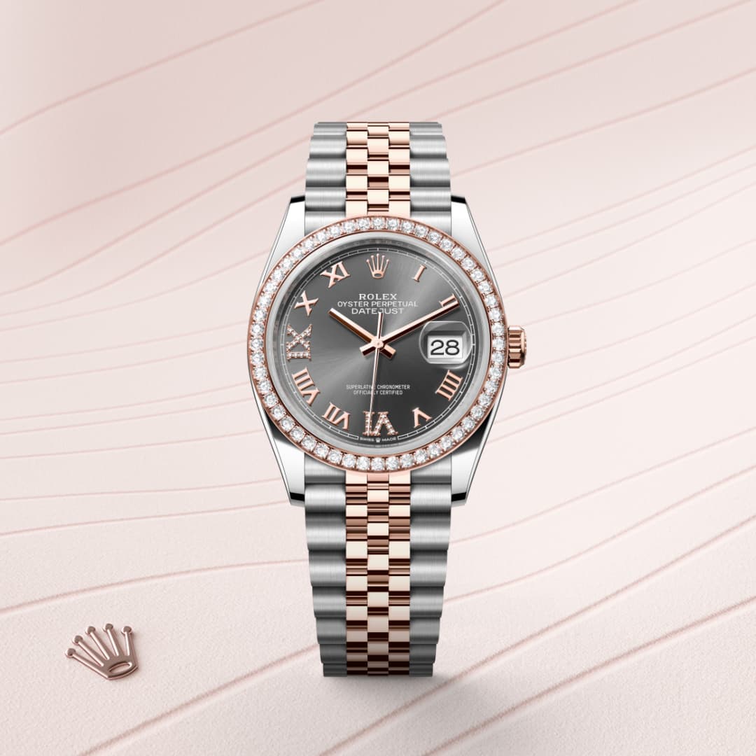 A Rolex watch with a silver and rose gold band, diamond bezel, and Roman numerals, displayed on a pink background.