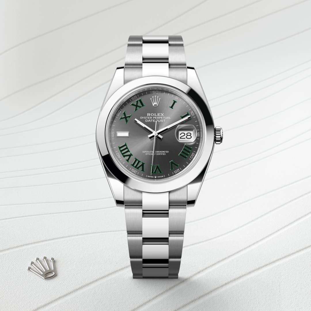A silver Rolex watch with a grey face, green Roman numerals, and a date window on a textured white surface.