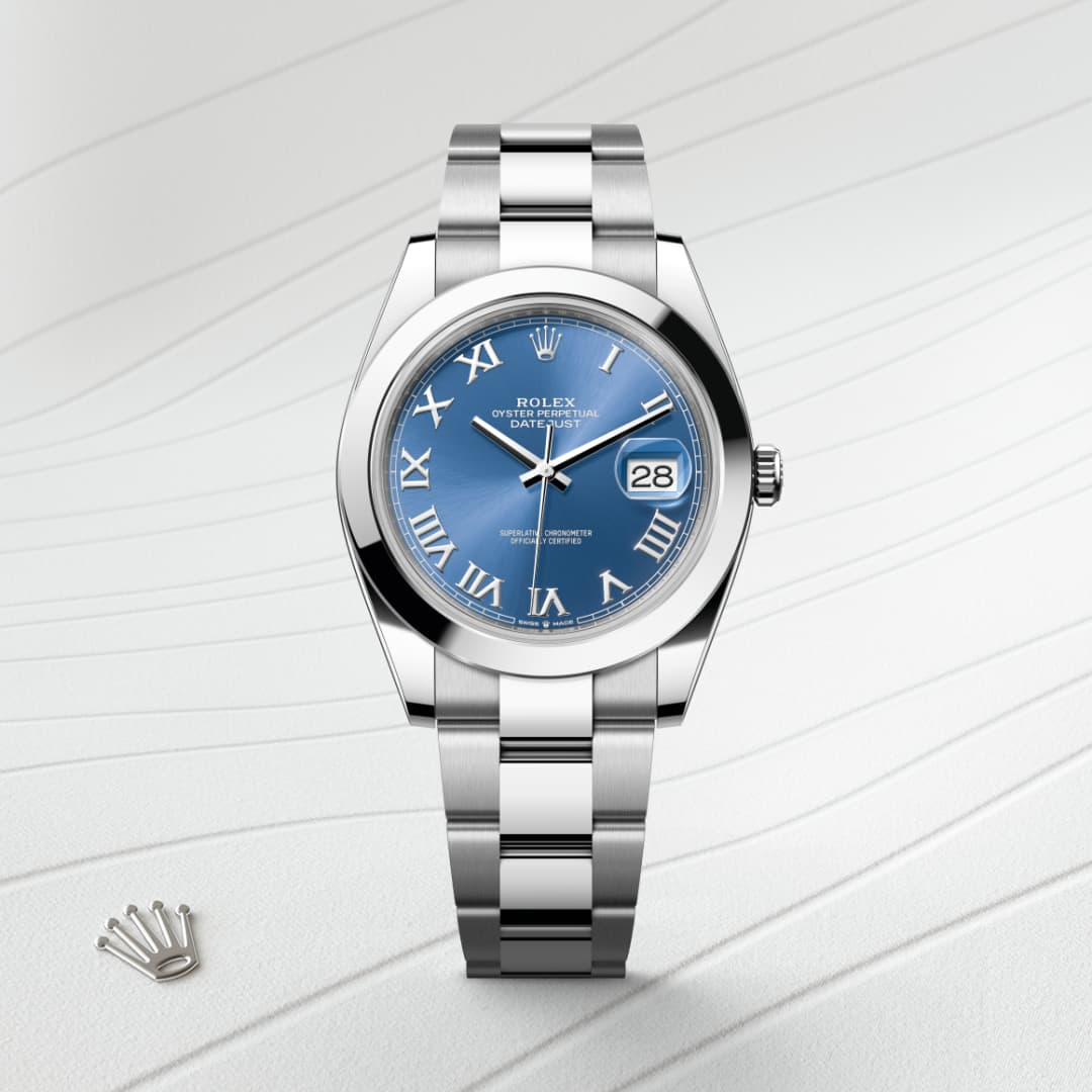 Silver Rolex watch with a blue face, Roman numerals, and date display, on a textured white background.