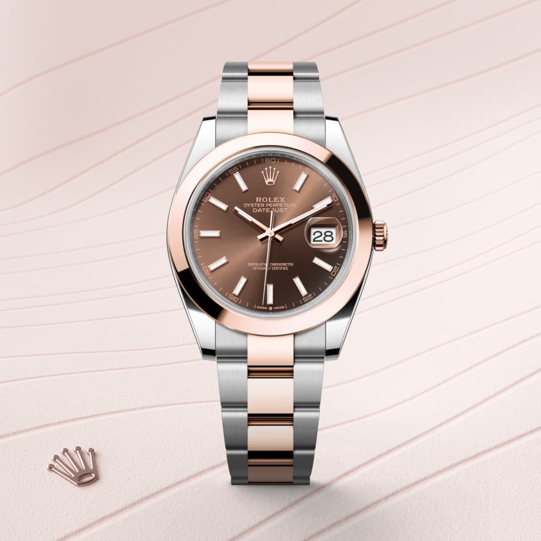 A two-tone Rolex watch with a brown dial and date display, set on a pink and white patterned background.
