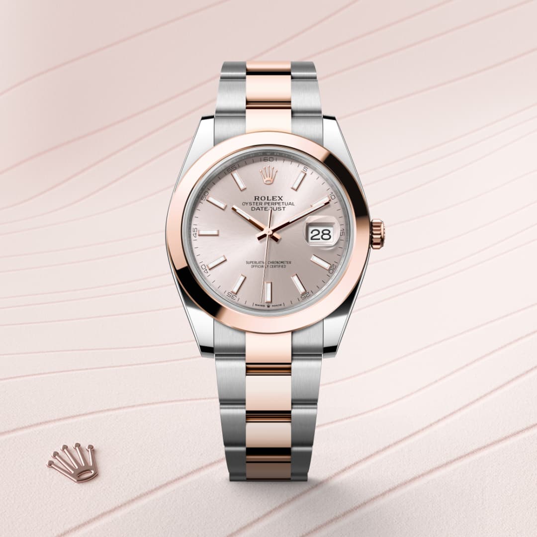 A Rolex watch with a silver and rose gold band, pink dial, and date display, shown on a textured background.