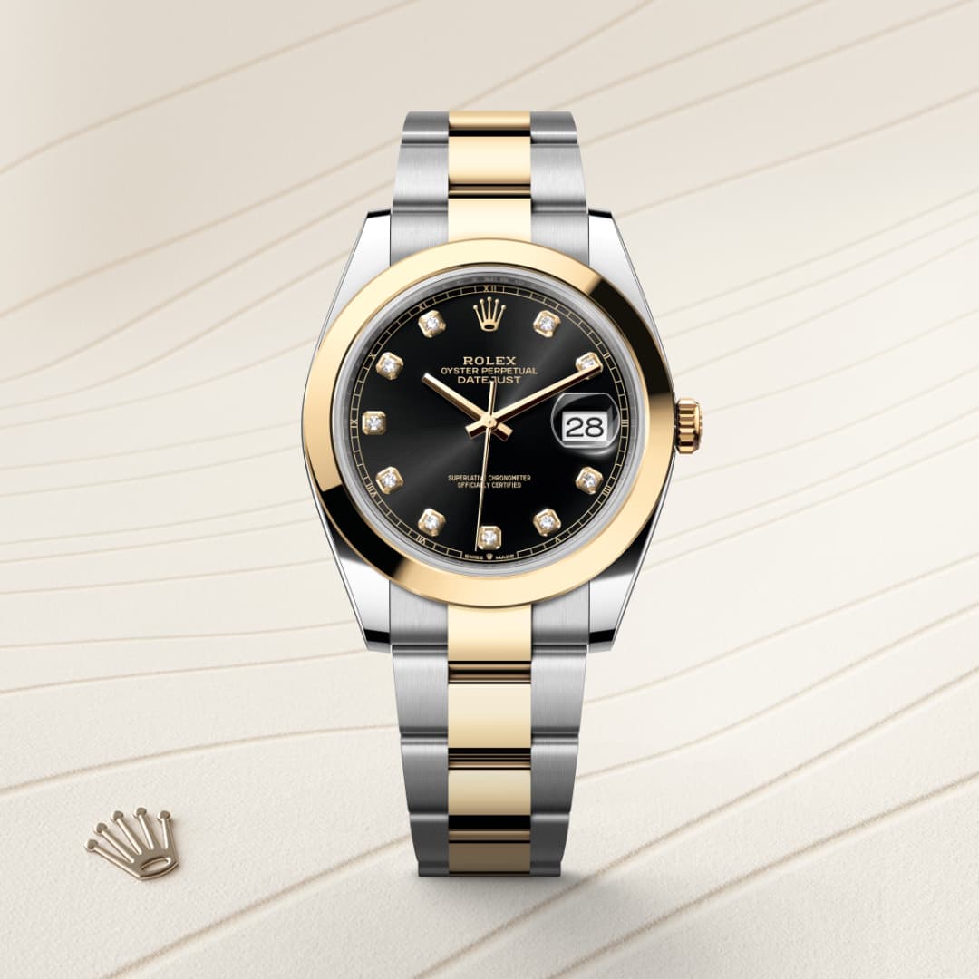 A two-tone Rolex watch with a black dial, diamond hour markers, and a date window, displayed on a patterned surface.