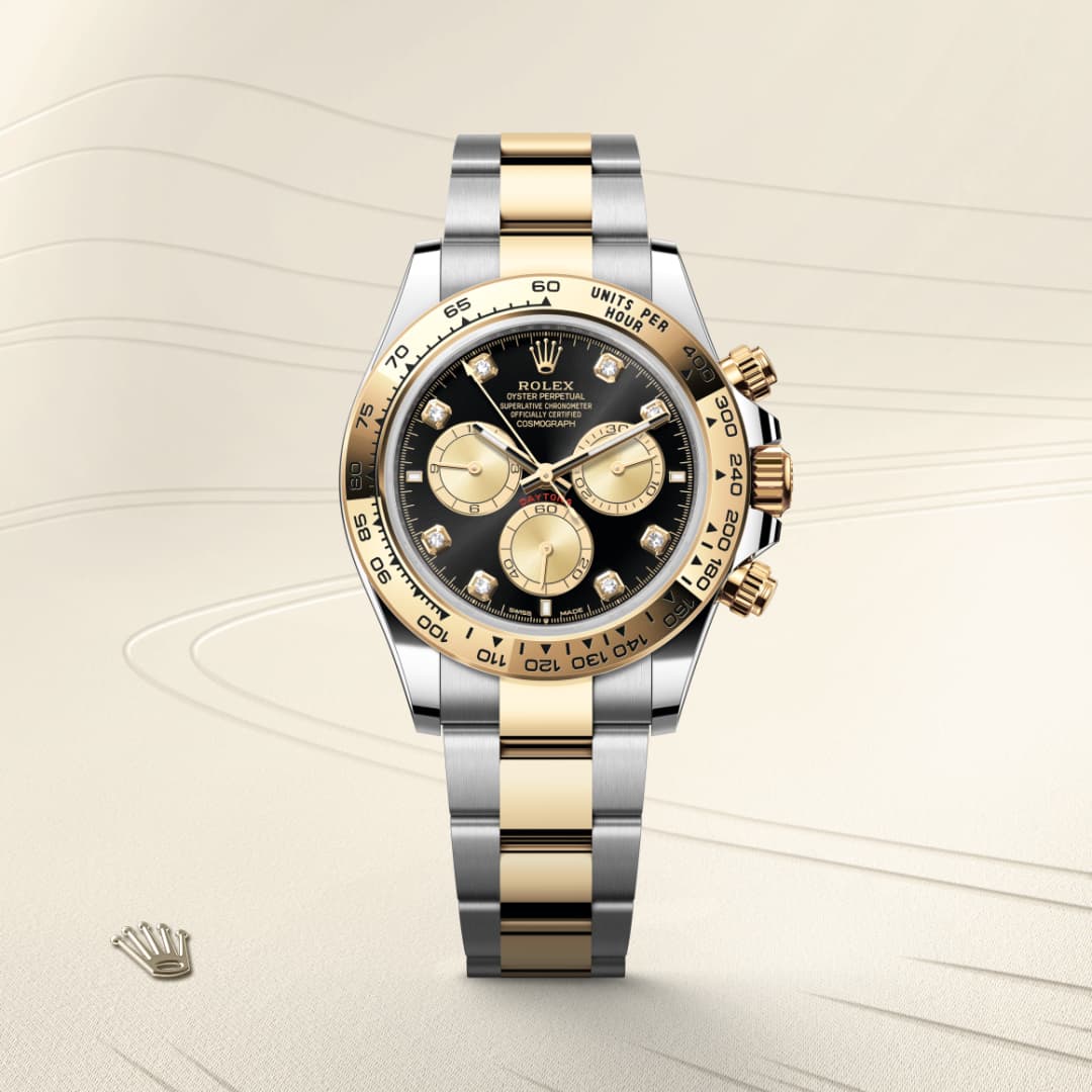 A two-tone Rolex chronograph watch with gold and silver bracelet on a cream textured background.