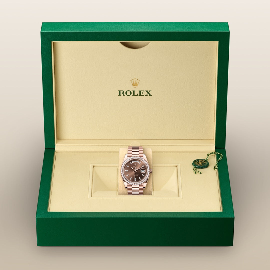 A Rolex watch with a brown face in a green and beige Rolex box with a green tag.