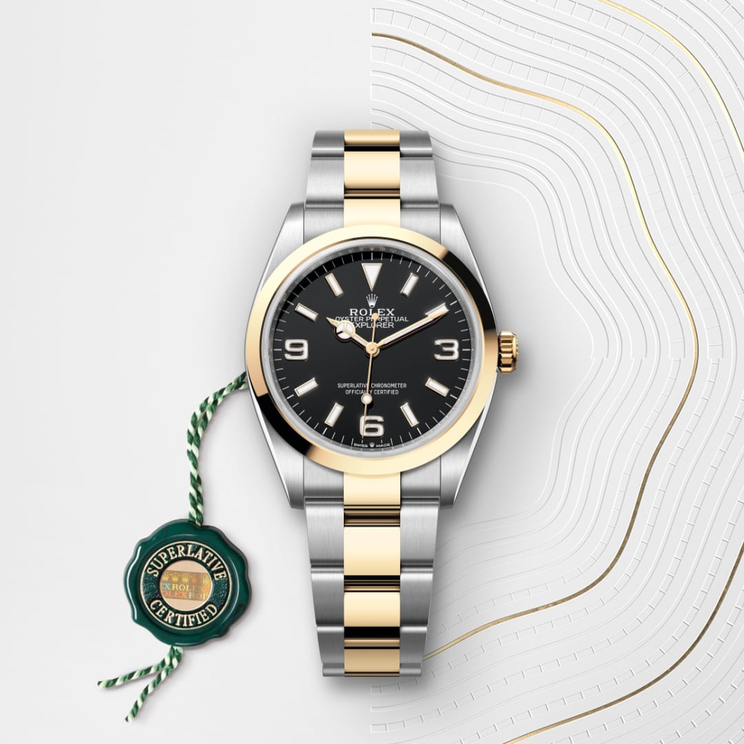 A two-tone Rolex watch with a black dial and gold accents, displayed beside a green “Superlative Certified” tag.
