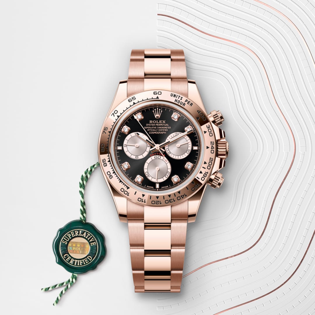 A rose gold Rolex watch with a black dial and three subdials, shown with a green Superlative Certified tag.