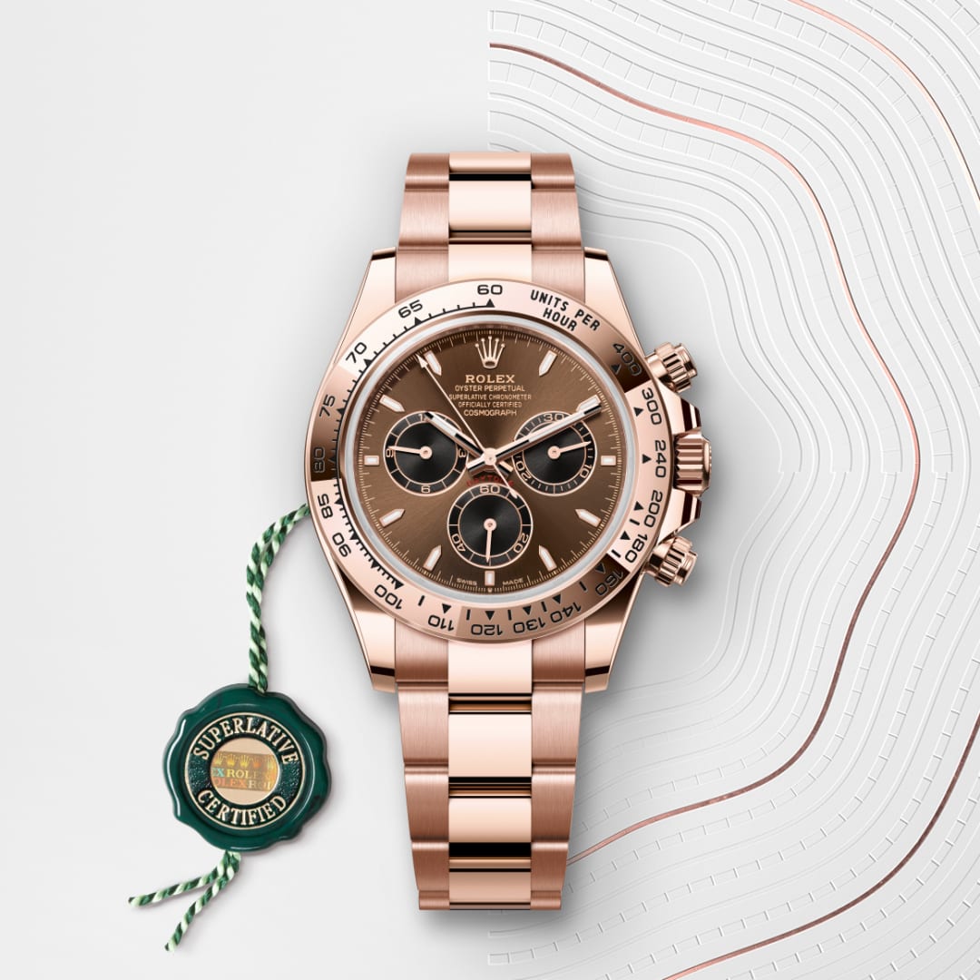 A rose gold Rolex Daytona watch with a brown dial and a green certification tag, displayed on a white background.