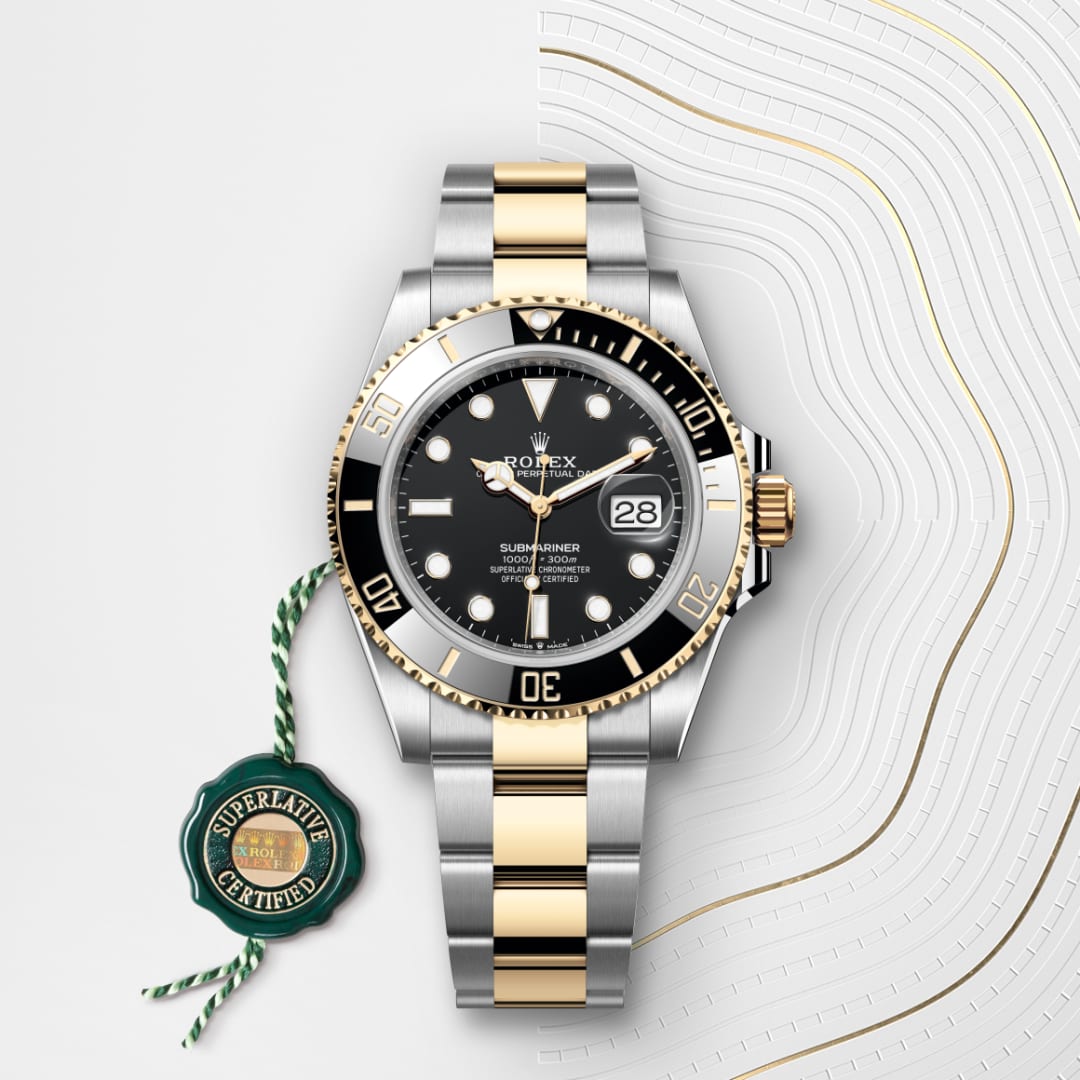 A Rolex Submariner watch with a black bezel, gold and silver bracelet, and a “Superlative Certified” tag.