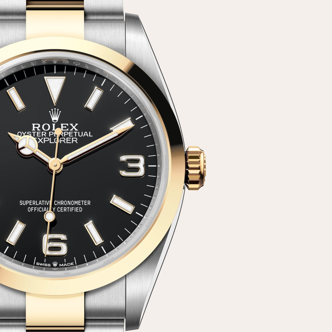 Close-up of a Rolex Oyster Perpetual Explorer watch with a black dial and gold accents on a metal band.