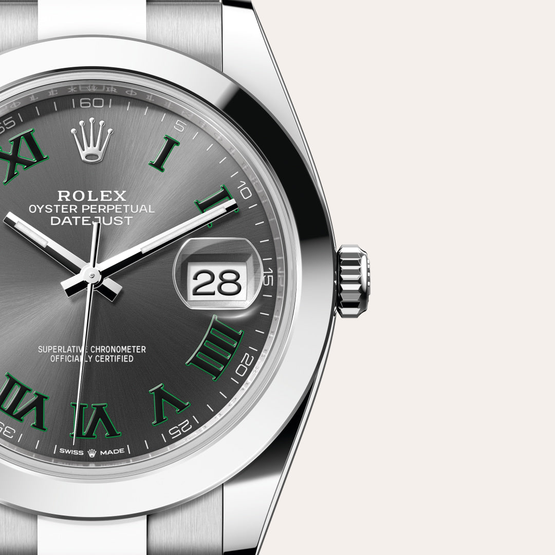 Close-up of a Rolex Datejust watch with a gray dial, green Roman numerals, and date display at 3 o’clock.
