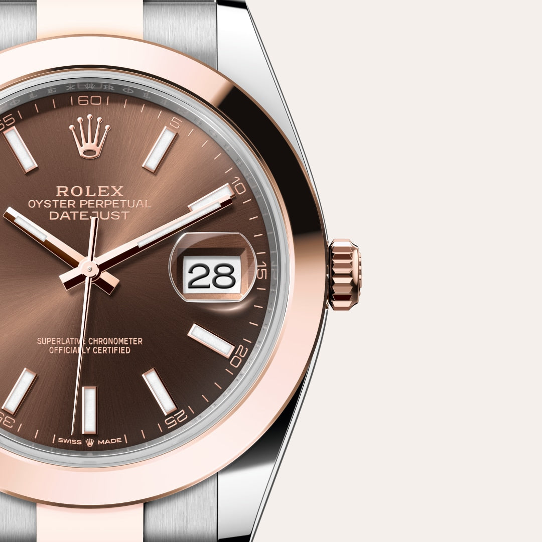 A close-up of a Rolex Oyster Perpetual Datejust watch with a brown dial and rose gold accents, showing the date 28.