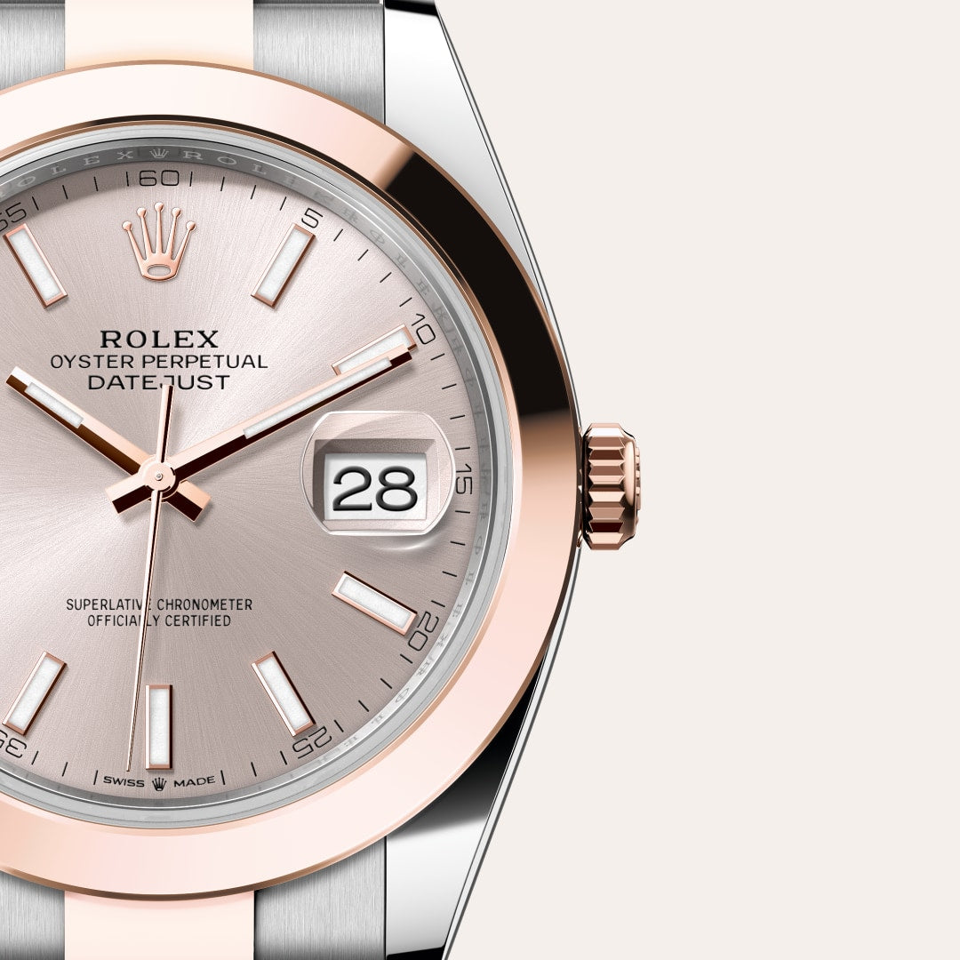 Close-up of a Rolex Oyster Perpetual Datejust watch with a silver dial and rose gold accents, showing the date 28.