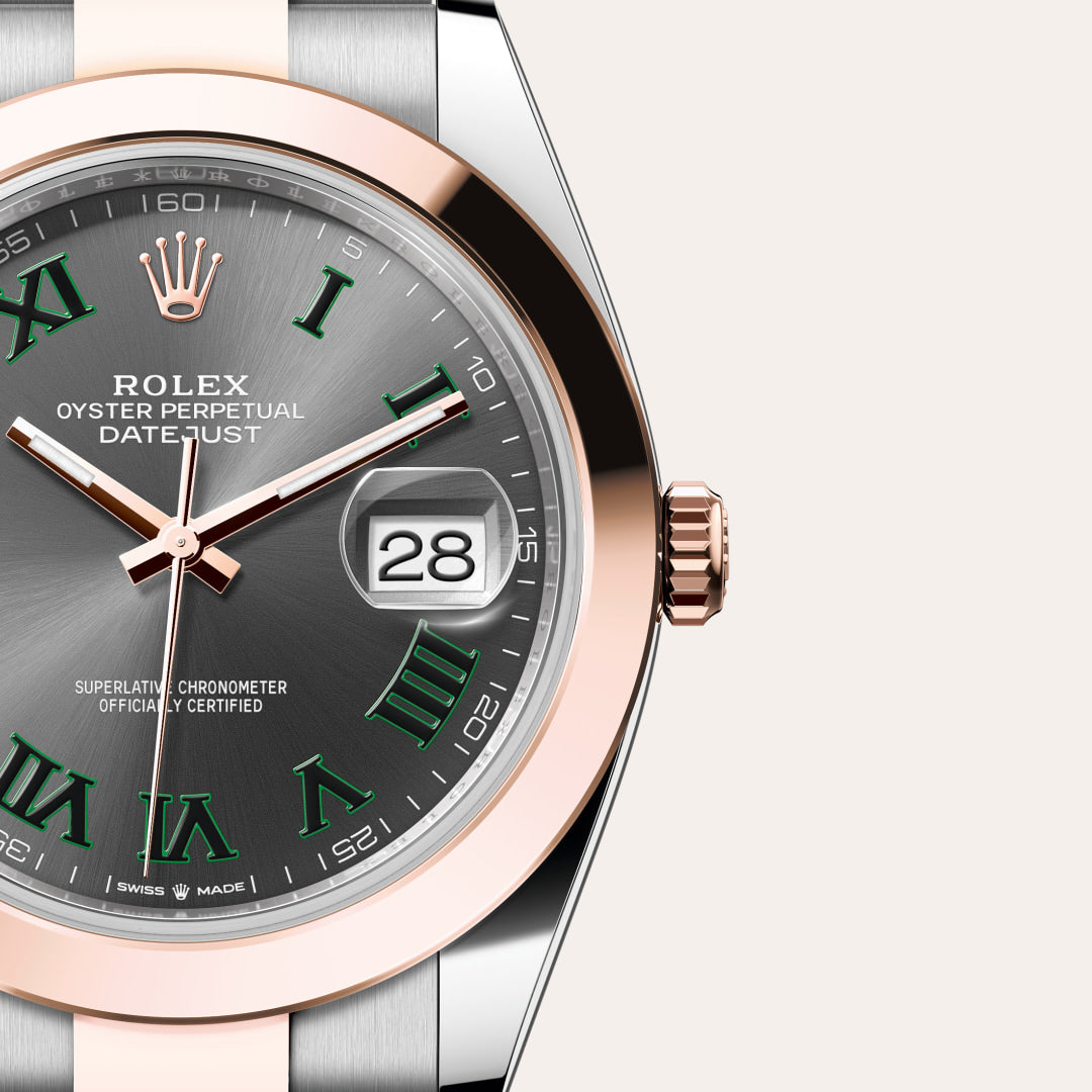 Close-up of a Rolex Datejust watch with a gray dial, green Roman numerals, and a two-tone metal case.