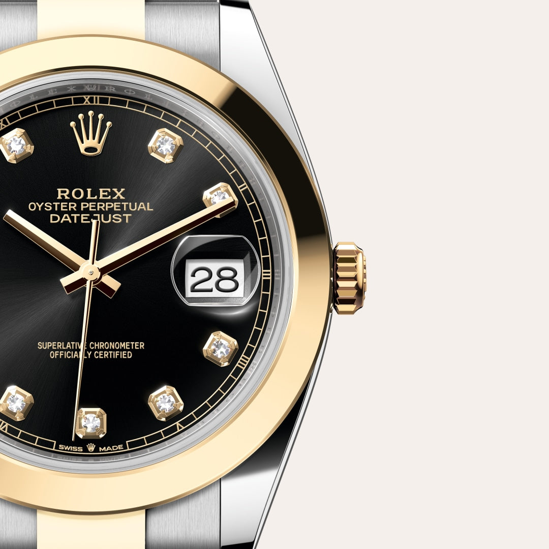 Close-up of a Rolex Datejust watch with a black dial, gold accents, and diamond hour markers showing the 28th.