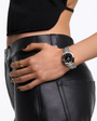 Model wearing the OMEGA Seamaster Aqua Terra 150M 30mm Steel on Steel Black Dial watch styled with black leather pants and a black top