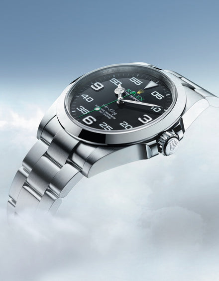 Silver Rolex watch with a black dial, floating above clouds against a blue sky background.