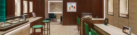 Modern luxury watch boutique with wood paneling, green accents, and display cases showcasing watches.