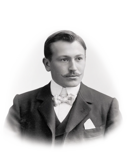 A man in a suit with a bow tie and mustache, posing for a black-and-white vintage portrait.