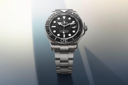 A silver metal watch with a black dial and bezel displayed against a gradient background.