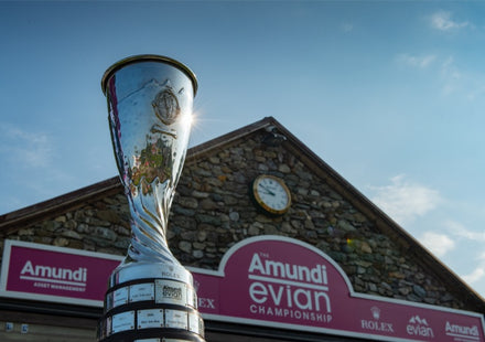 Silver trophy in front of a stone building with Amundi Evian Championship signs and a clock.