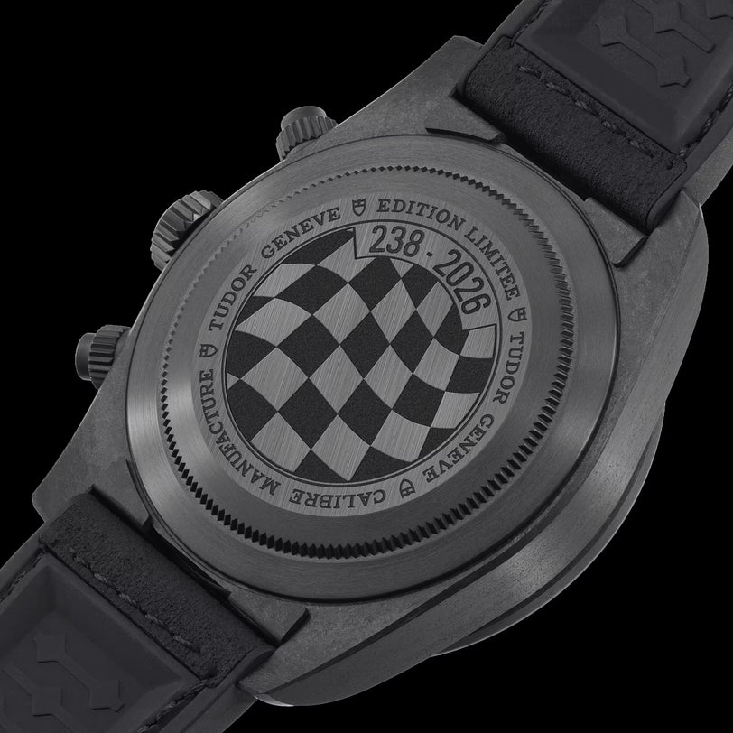 Black Bay Chrono Carbon watch with checkered dial, chronograph pushers, and black rubber strap shown from caseback view.