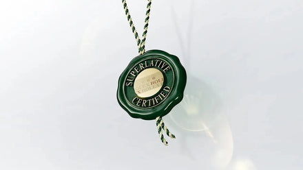 A green wax seal tag with Superlative Certified text, attached to a twisted green and white string.
