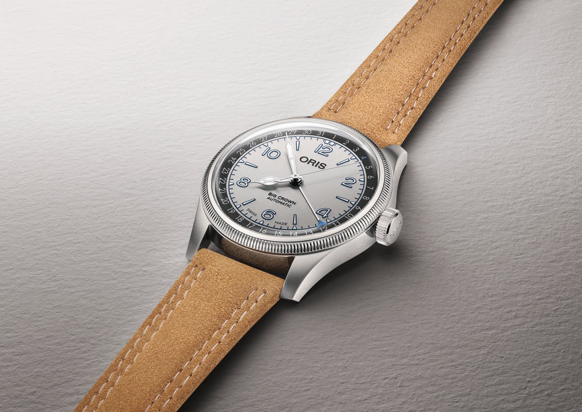 Silver-tone watch with white dial, Arabic numerals, and tan leather strap with contrast stitching.