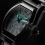 Black stainless steel watch with tonneau case, silver dial, blue Roman numerals, luminous hands, and metal bracelet.
