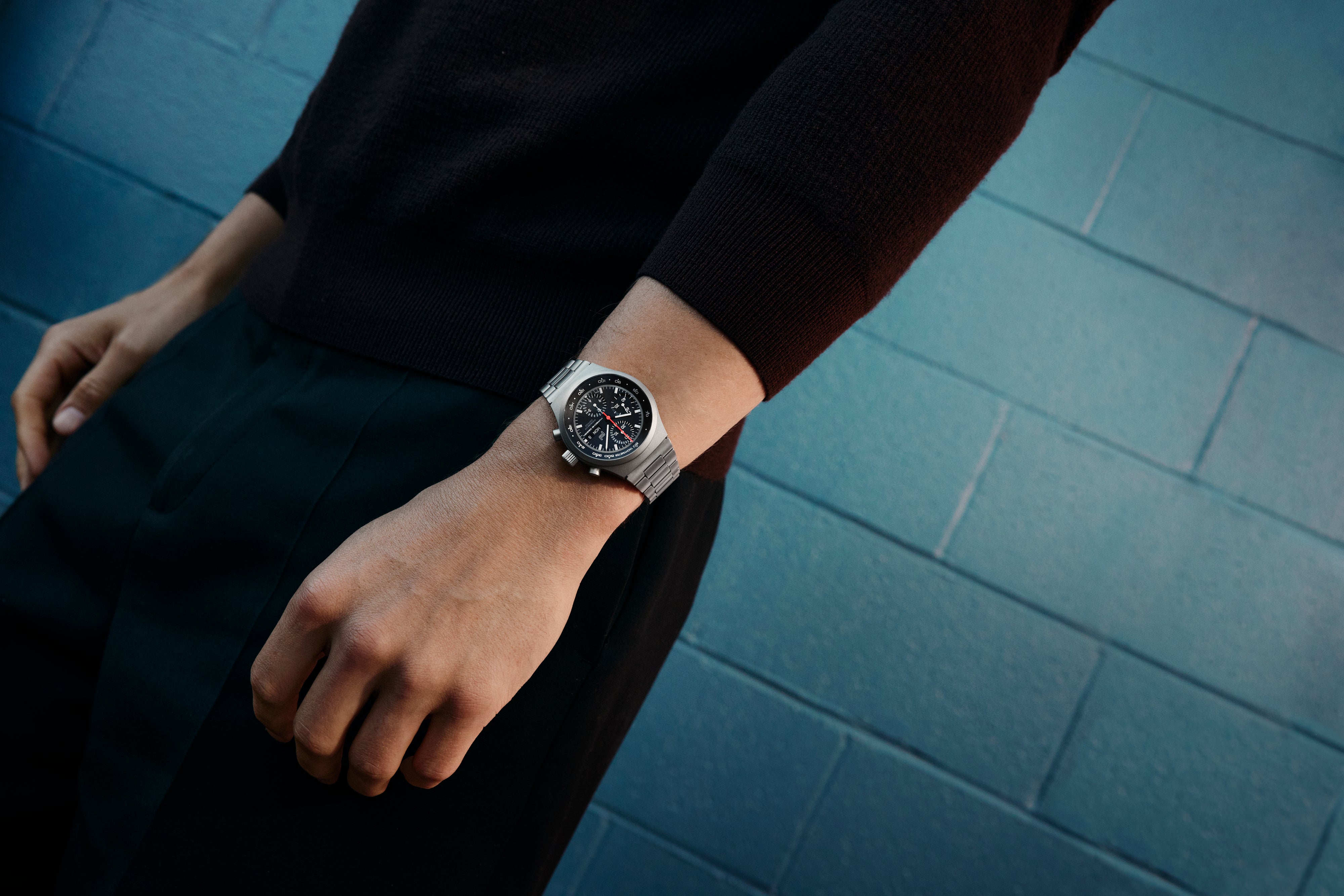 Person wearing a silver watch on a blue tiled floor