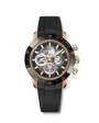 Rose gold chronograph watch with black dial, visible movement, black rubber strap, and tachymeter bezel.