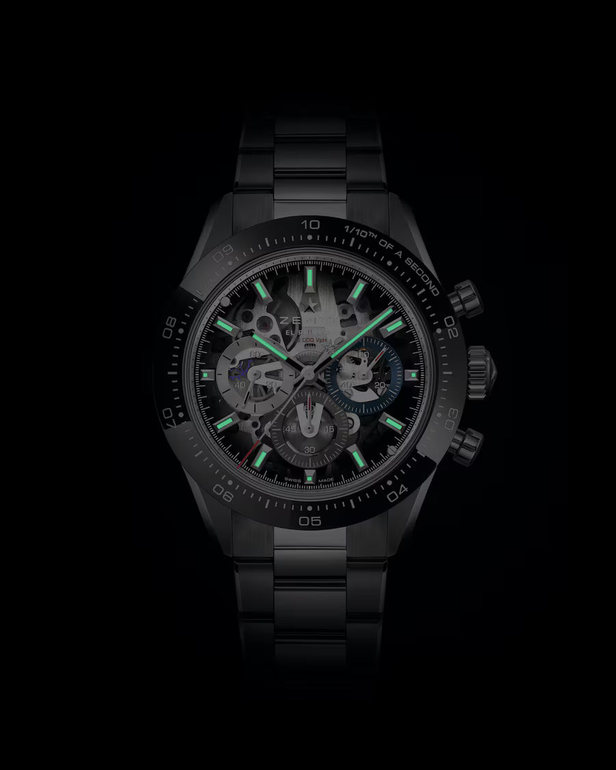 Black stainless steel chronograph watch with skeleton dial, green luminous hands and hour markers, and tachymeter bezel.