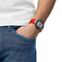 Person wearing a watch with a red strap on a white background