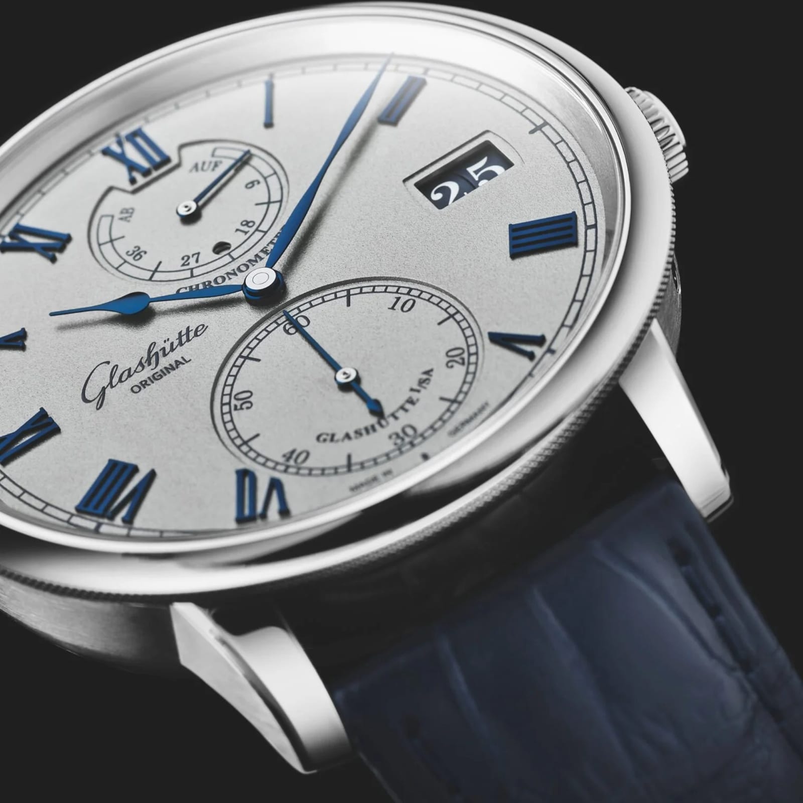 Close-up of the Glashütte Original Senator Chronometer, featuring blue Roman numerals, subdials, and a blue leather strap—a striking showcase of German watchmaking against a black background.
