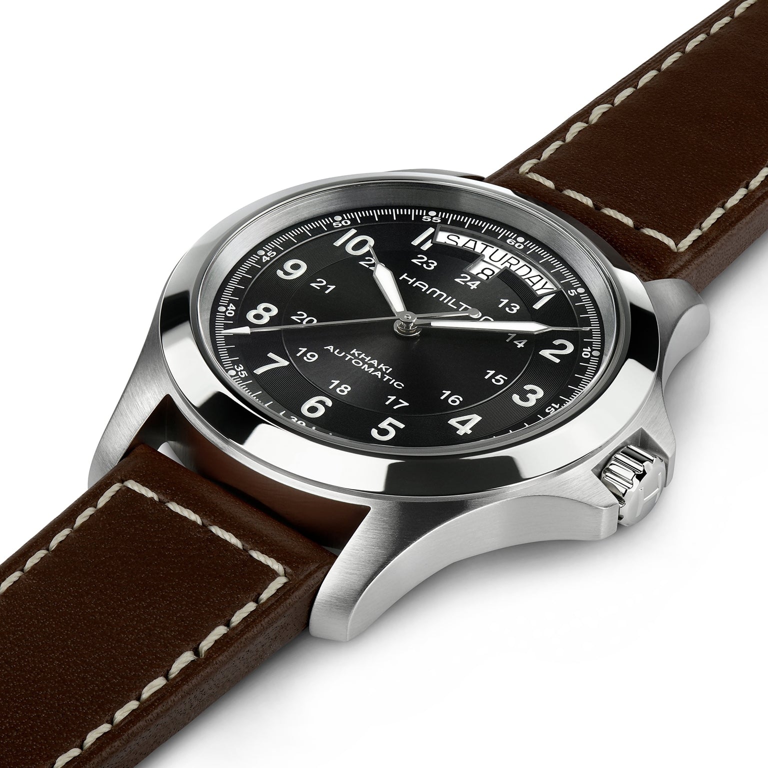 A close-up of the Hamilton Khaki Field King Auto wristwatch featuring a black dial with military time, white numerals, and a brown leather strap with white stitching.