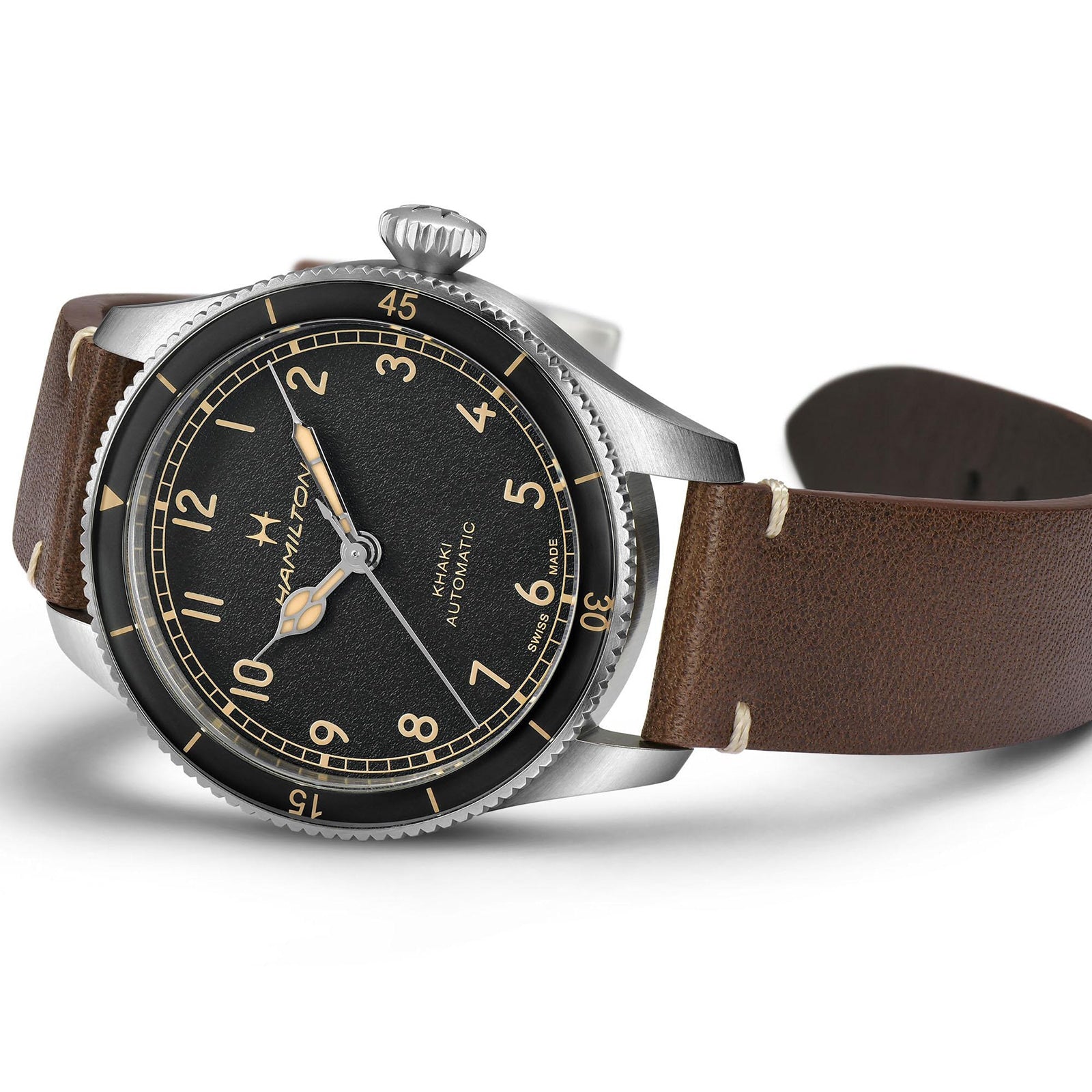 The Hamilton Khaki Aviation Pilot Pioneer watch features a black dial with beige numerals and a brown leather strap, shown at an angle.