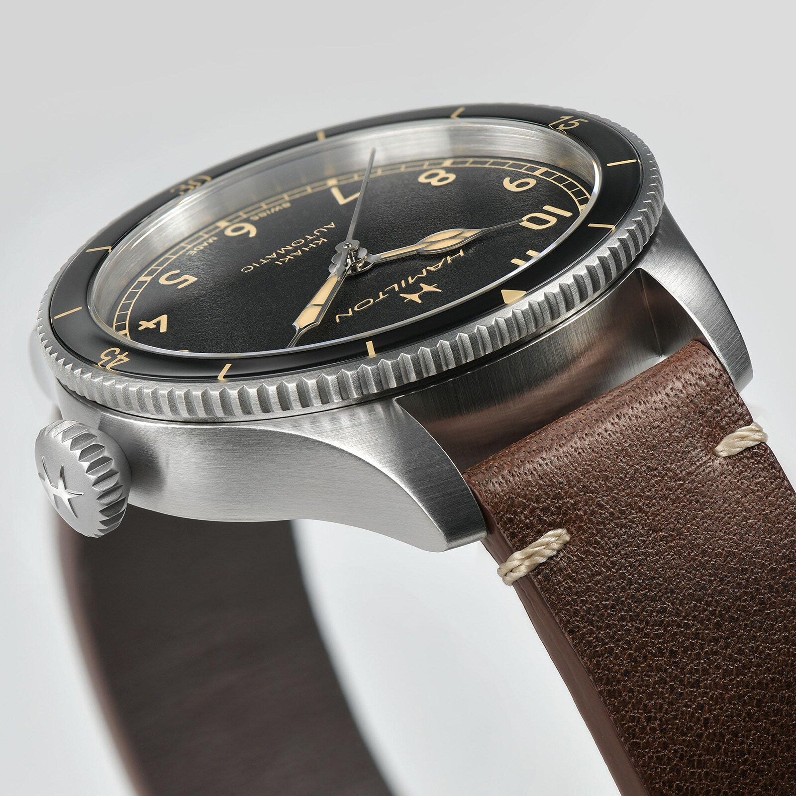 A close-up of the Hamilton Khaki Aviation Pilot Pioneer watch, featuring a black dial, silver case, and brown leather strap.