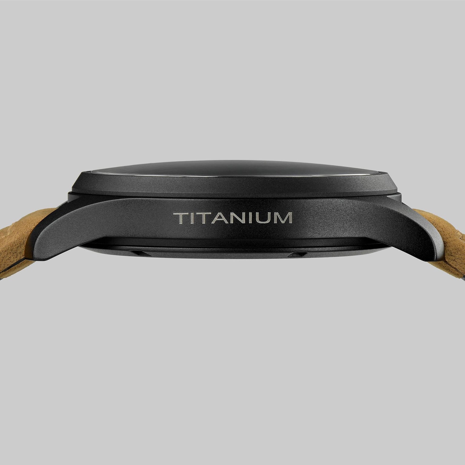 Side view of the Hamilton Khaki Field Titanium Auto, featuring a dark military-style titanium case engraved with TITANIUM and light brown leather straps, set against a plain gray background.