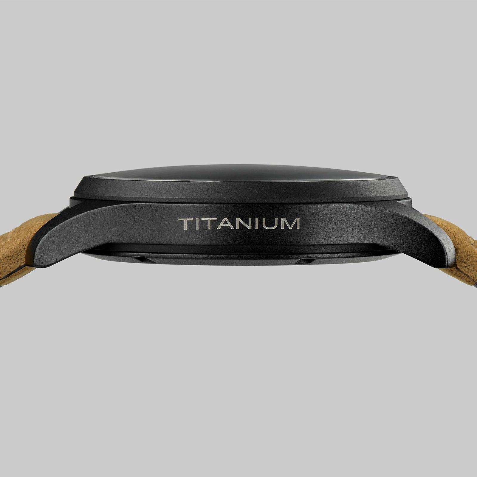 Side view of the Hamilton Khaki Field Titanium Auto, featuring a dark military-style titanium case engraved with TITANIUM and light brown leather straps, set against a plain gray background.